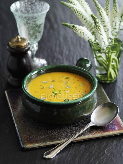 Butternut squash soup in green dish over dark wooden surface — Stock Photo