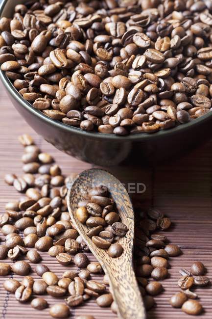 Grains de café dans un bol et sur cuillère — Photo de stock
