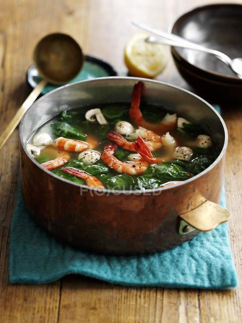 Крупним планом суп з морепродуктів з креветками та зеленню в горщику — стокове фото
