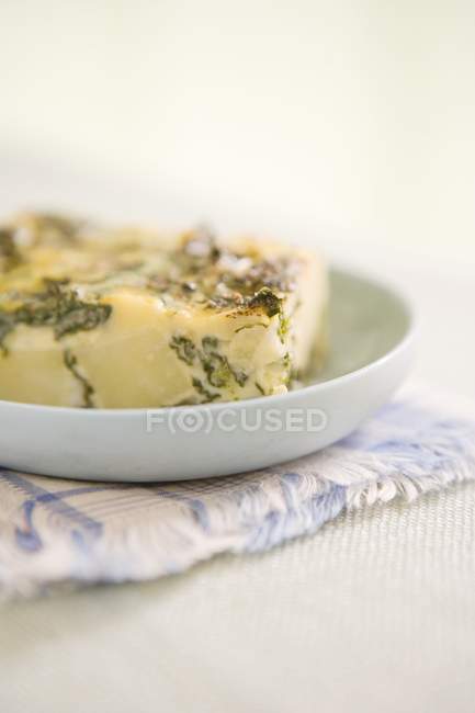 Potato and spinach frittata  on white plate over towel — Stock Photo