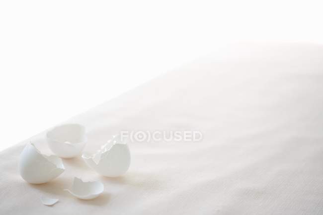 Elevated view of white egg shells on a white tablecloth — Stock Photo