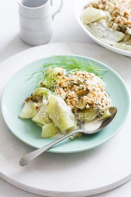 Fennel gratin on green plate with spoon — Stock Photo