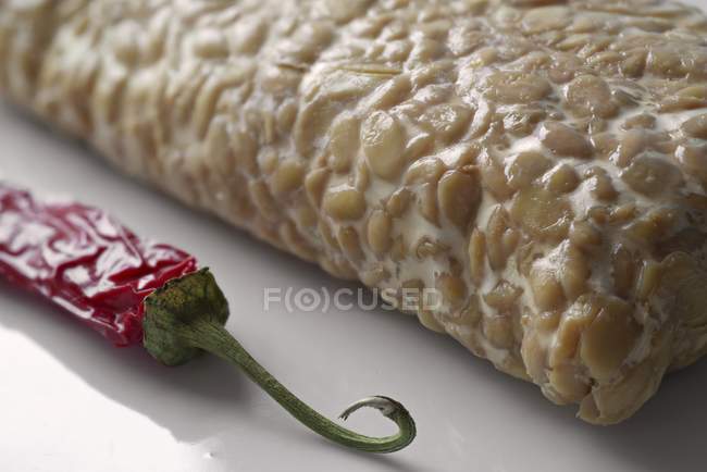 Tempeh - fermented soya beans and dried chilli pepper on white surface — Stock Photo