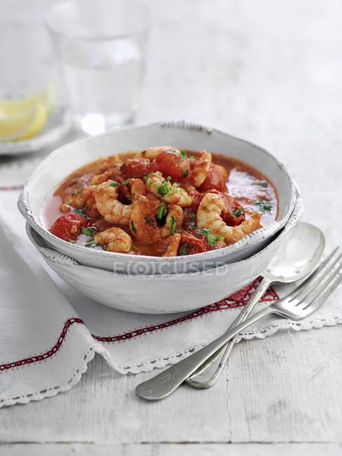 Zuppa di pomodoro e gamberetti con prezzemolo su piatto bianco su asciugamano con cucchiaio e forchetta — Foto stock