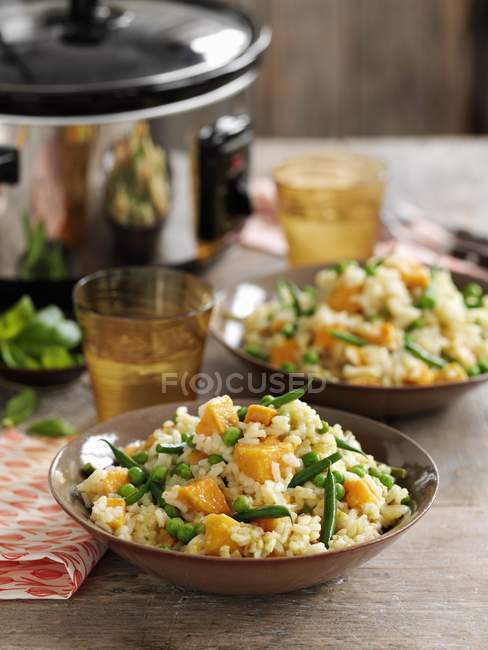 Risotto with green beans and sweet potatoes on plates over table — Stock Photo