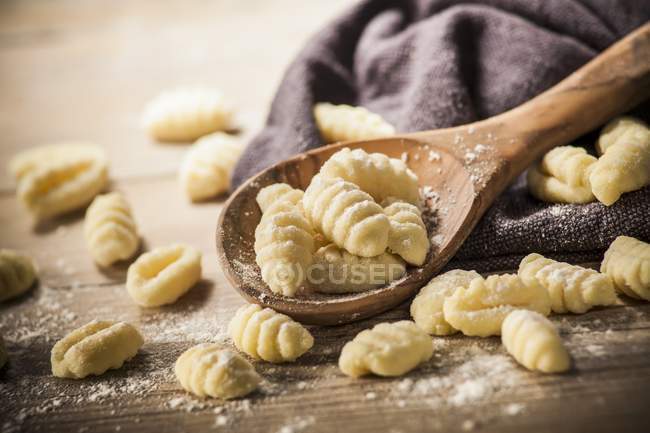 Gnocchis frais avec farine sur cuillère et tissu en bois — Photo de stock