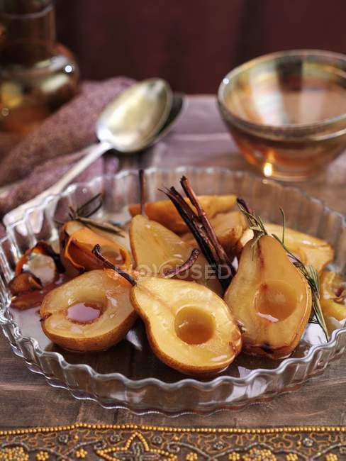 Vue rapprochée de poires caramélisées rôties avec bâtonnets de cannelle — Photo de stock