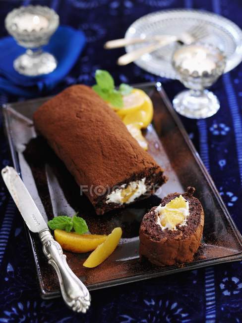 Closeup view of chocolate Swiss roll with peaches — Stock Photo