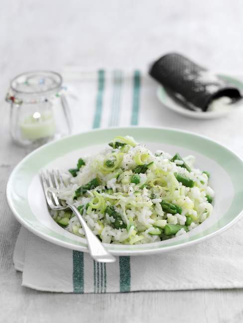 Risotto con asparagi verdi su piatto con forchetta sopra asciugamano — Foto stock