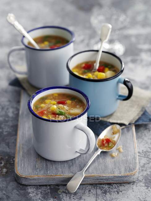 Quinoa and sweetcorn soup in enamel cups — Stock Photo
