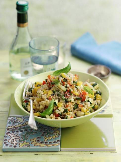 Quinoa pilau with vegetables in green plate with fork — Stock Photo