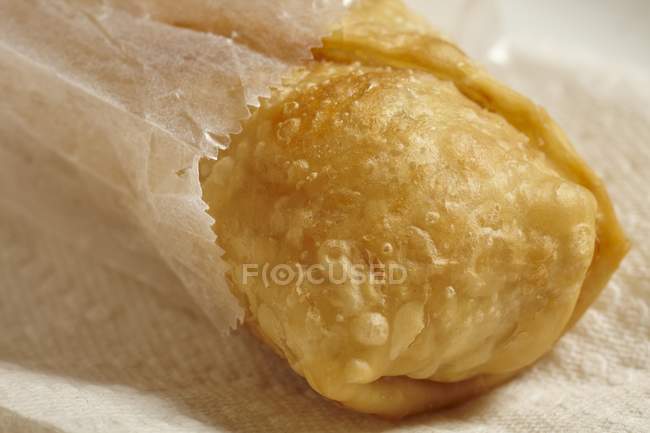 Vista close-up de um rolo frito em um saco de papel — Fotografia de Stock