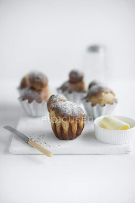 Closeup view of Brioches on a chopping board with butter and a knife — Stock Photo