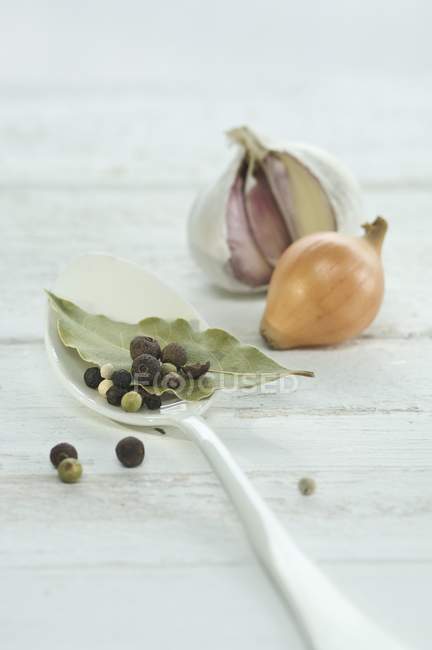 Bay leaf and pepper corns on spoon — Stock Photo