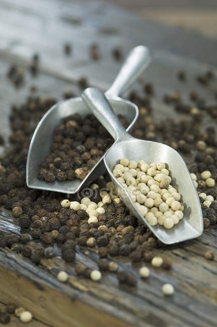 Black and white pepper in scoops — Stock Photo