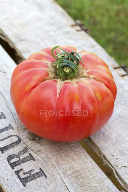 Red tomato on wooden crate — Stock Photo