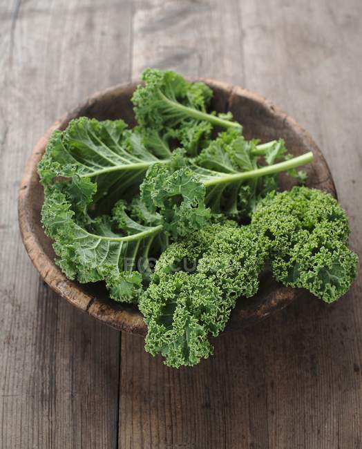 Green kale in wooden bowl — Stock Photo
