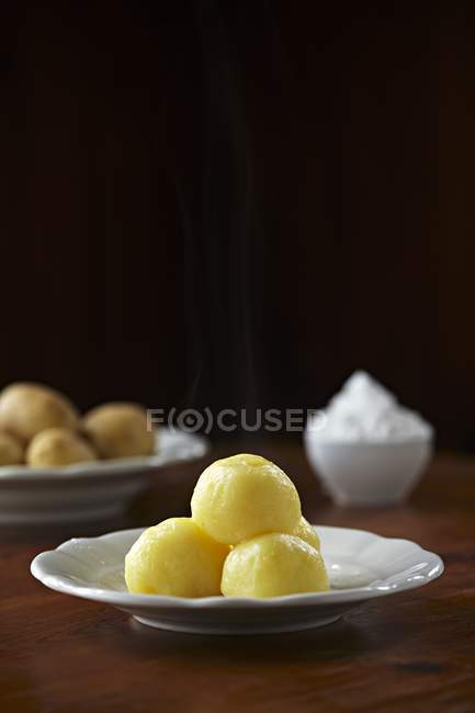 Potato dumplings with ingredients on white plates over table — Stock Photo