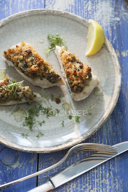 Chicken with a shallot crust and cress on plate over blue woden surface — Stock Photo