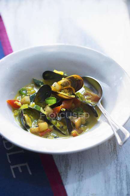 Muscheleintopf mit Gemüse auf weißem Teller mit Löffel — Stockfoto
