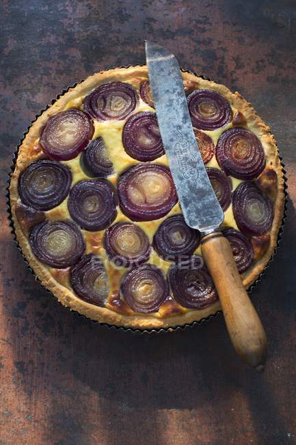 Red onion quiche in a baking tin with knife — Stock Photo