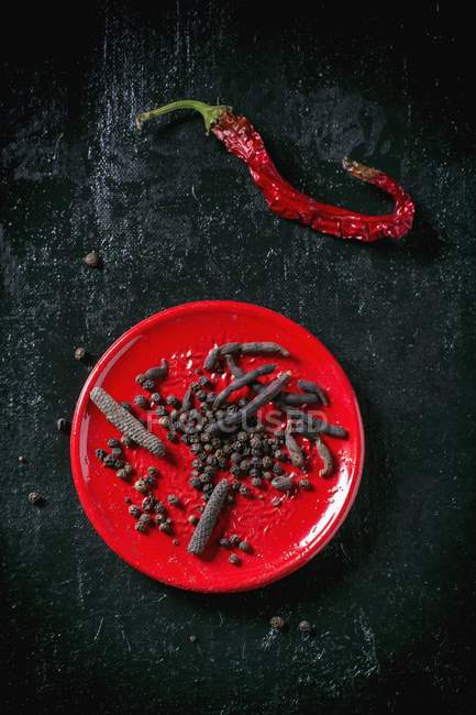 Pfefferkörner auf rotem Teller — Stockfoto