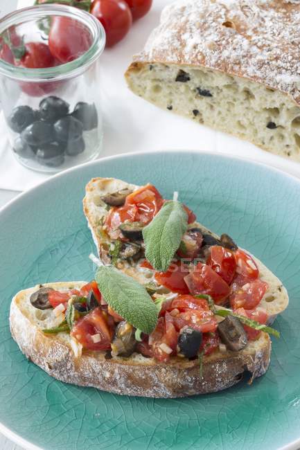 Брускетта з помідорами, оливками та шавлією на блакитній тарілці — стокове фото