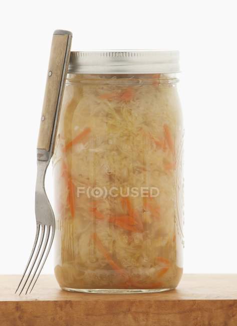 Un barattolo di crauti fatti in casa sul tagliere con la forchetta — Foto stock