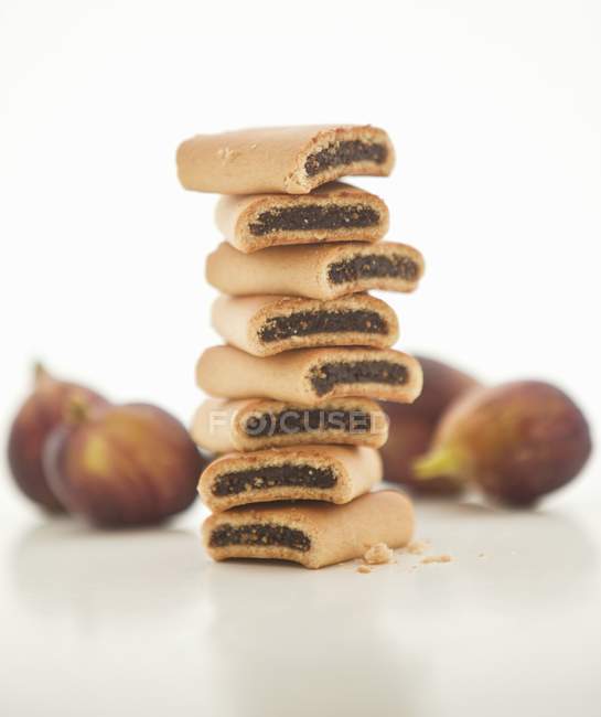 A stack of fig rolls with fresh figs in the background — Stock Photo
