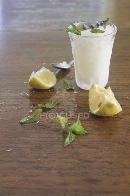 Closeup view of lemon granita with lemons and fresh mint on a wooden surface — Stock Photo