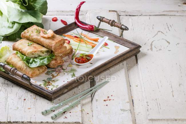Rollos de primavera con verduras y gambas servidos con una salsa picante en una bandeja - foto de stock