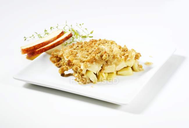 Vista ravvicinata di fette di mela e panetteria con briciole croccanti su piatto bianco — Foto stock