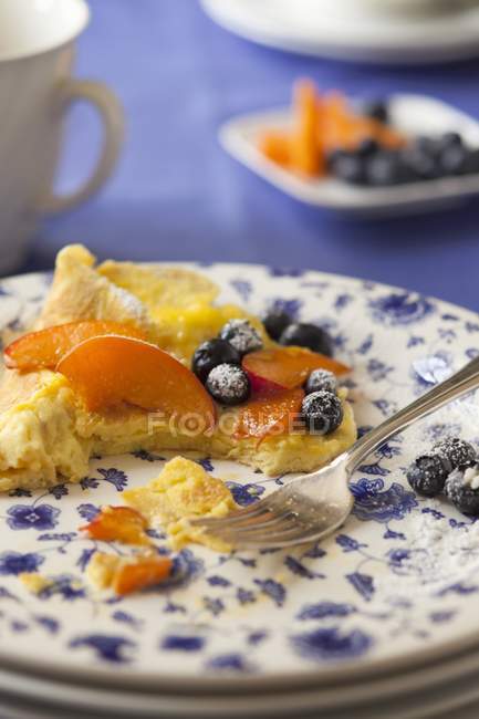 Süßes Omelette mit Blaubeeren, Pfirsichen und Puderzucker, teilweise verzehrt — Stockfoto