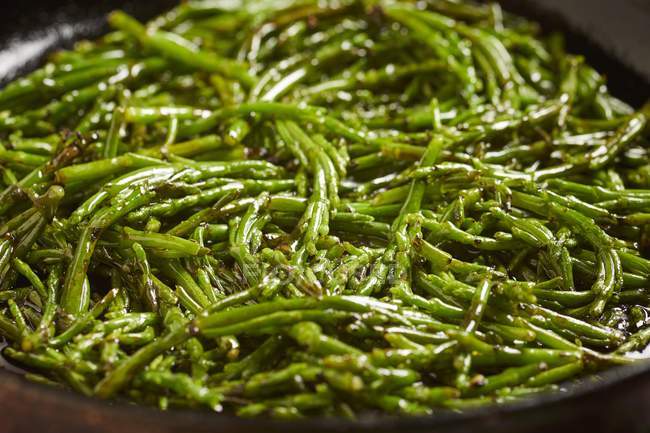 Samphire sauted in olive oil on black plate — Stock Photo