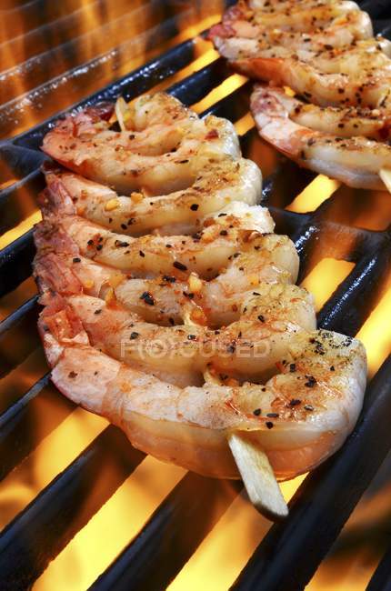 Closeup view of spicy prawn skewers on flaming grill — Stock Photo