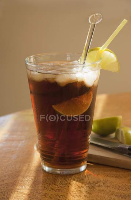 Closeup view of Cola with rum, limes and ice cubes in a ray of sunshine — Stock Photo