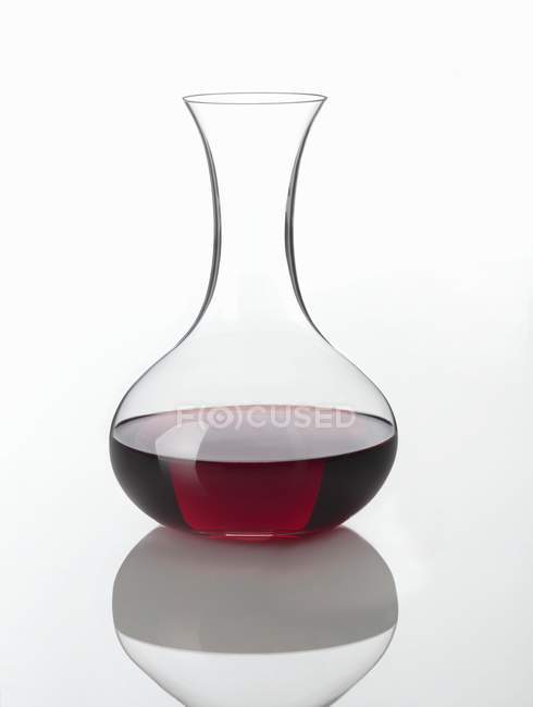 Vue rapprochée d'une carafe de boisson rouge sur une surface réfléchissante blanche — Photo de stock