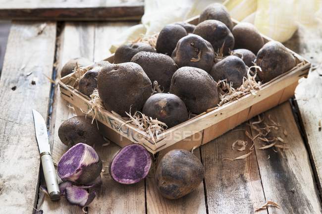 Purple potatoes in rustic wooden basket — Stock Photo