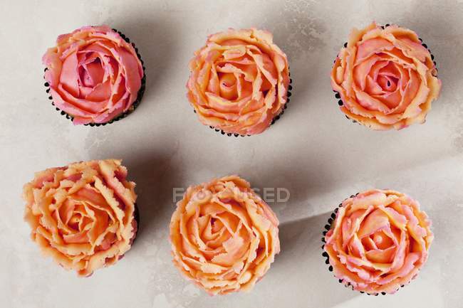Cupcake di rose disposti in file — Foto stock