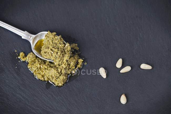 Nahaufnahme von oben Pesto auf Löffel und Pinienkernen — Stockfoto