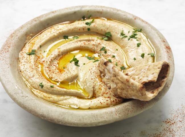 Closeup view of a bowl of hummus with crunchy pastry — Stock Photo