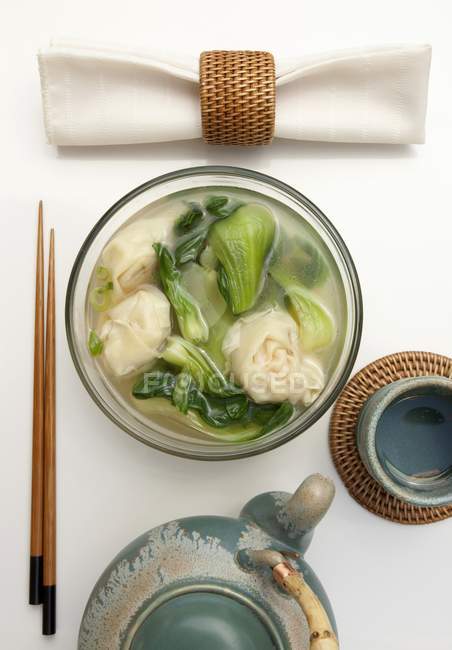 Креветочный суп с вонтонами и бок-чой на белой поверхности — стоковое фото
