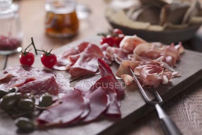 Cold cuts on wooden chopping board — Stock Photo
