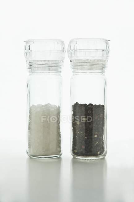 Salt and pepper in Plexiglass mills o — Stock Photo