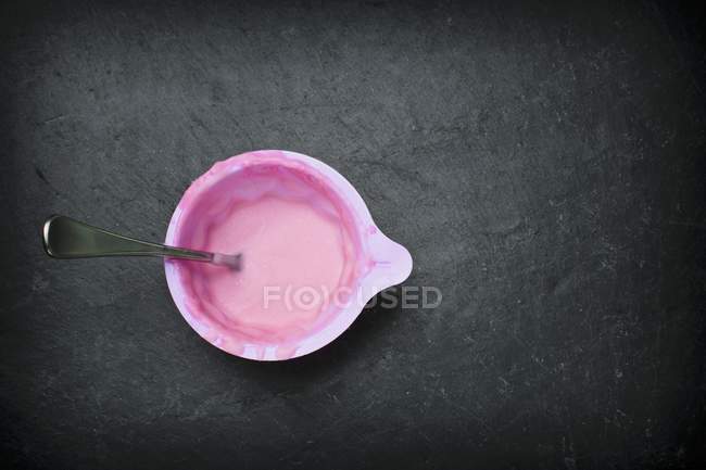 Closeup top view of chocolate-raspberry glaze in a plastic container with a spoon — Stock Photo
