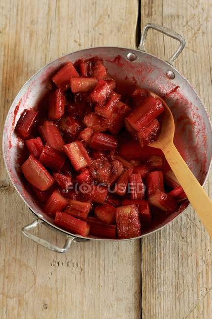Vue rapprochée de la rhubarbe caramélisée avec cuillère en bois dans la casserole — Photo de stock