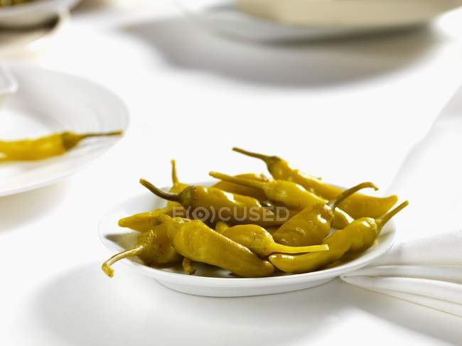 Pickled chillis on a plate on white plate — Stock Photo