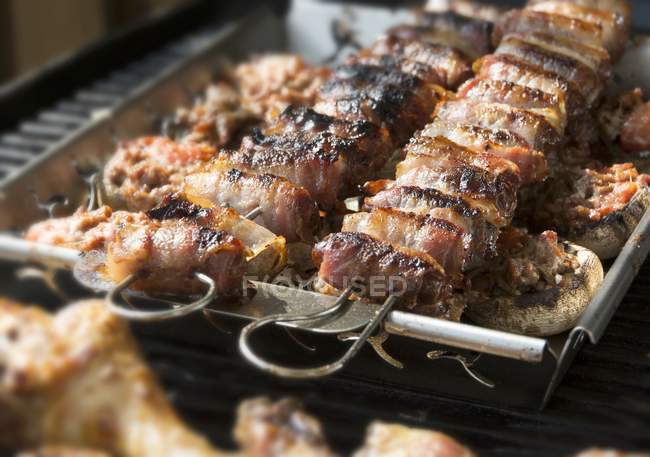 Closeup view of stuffed mushrooms and figs wrapped in bacon on a grill — Stock Photo
