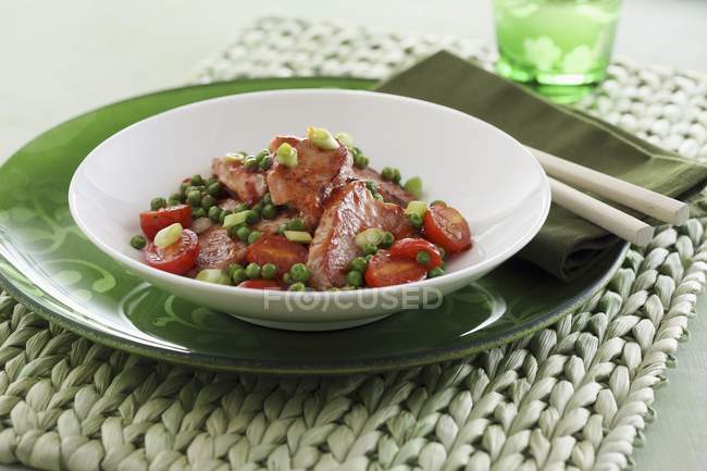 Sweet-and-sour pork loin with peas and tomatoes  on white plate — Stock Photo