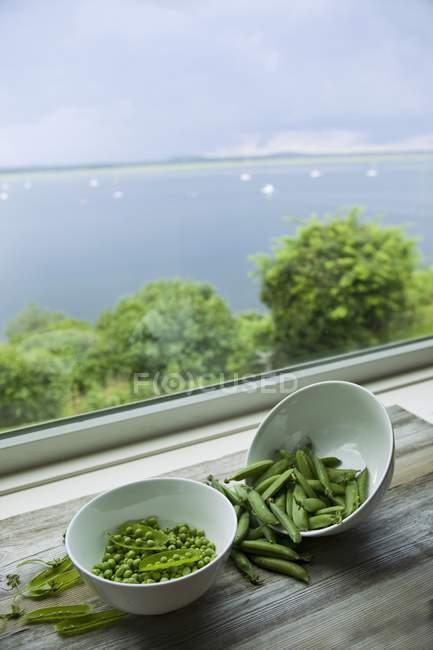 Ervilhas e vagens de ervilhas em taças — Fotografia de Stock